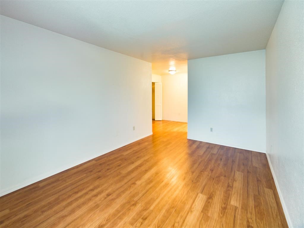an empty living room with wood floors and white walls