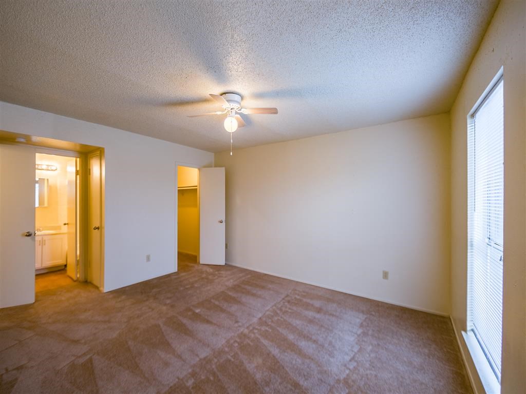 an empty living room with a ceiling fan and a window