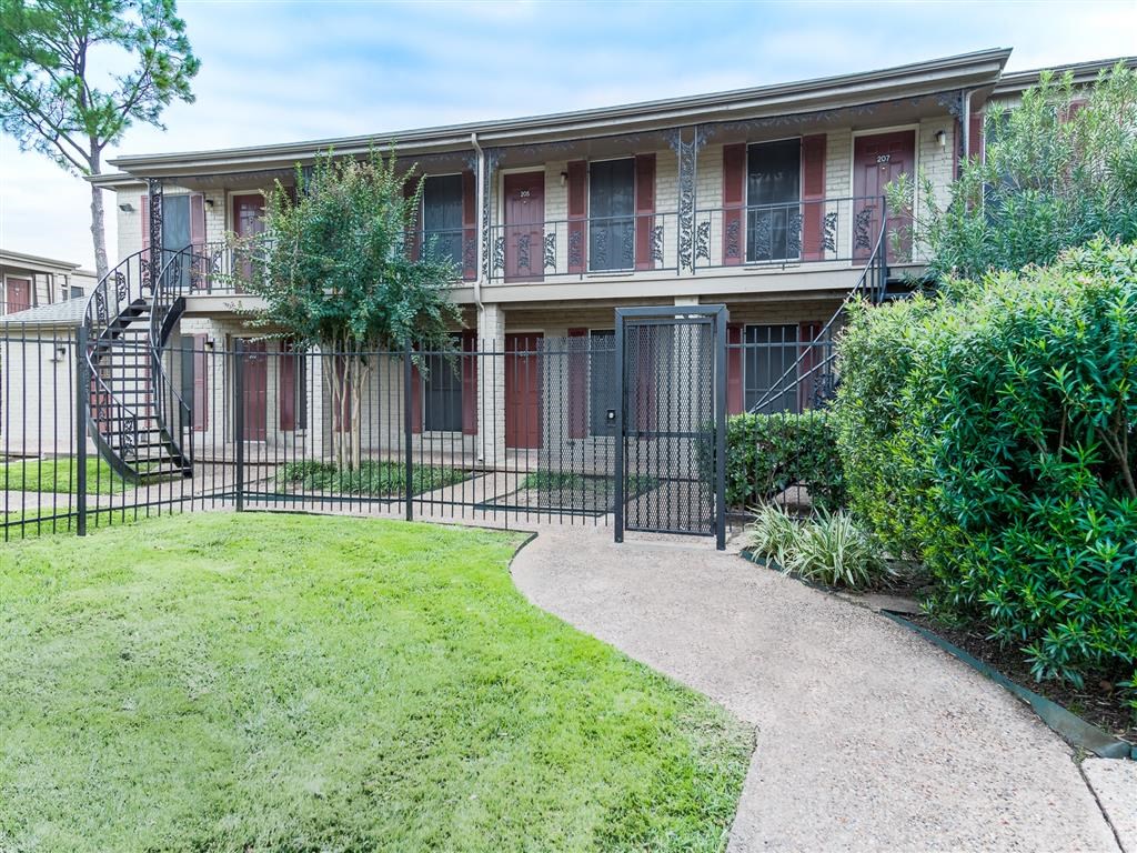 an apartment building with a yard and a gate