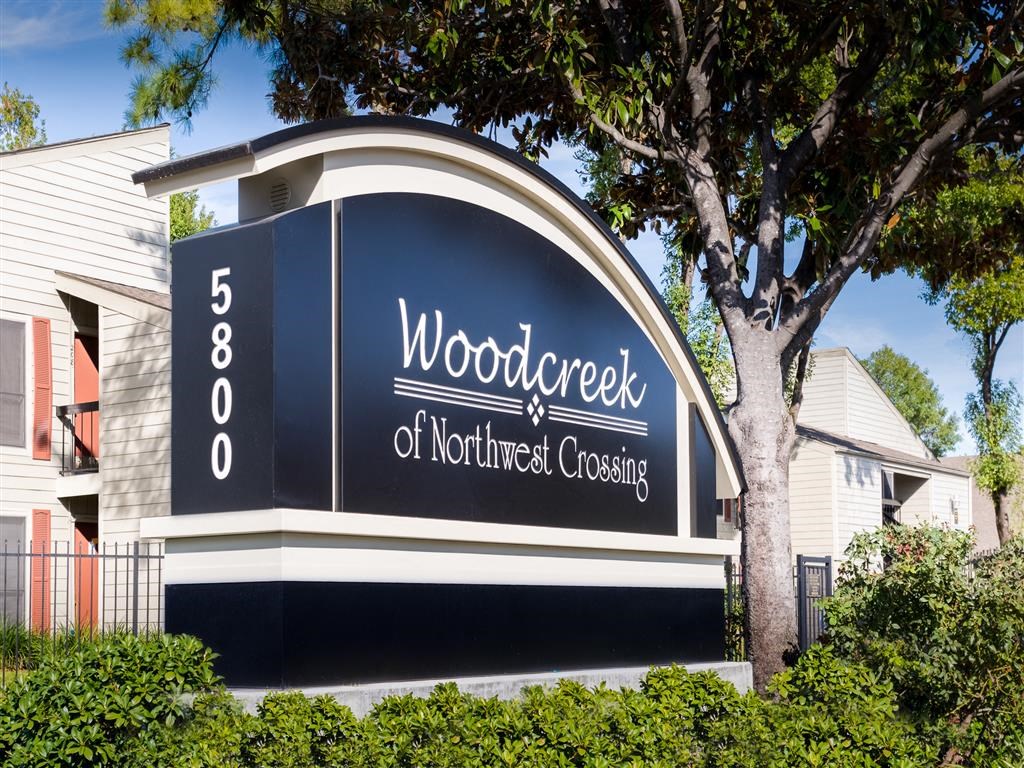 a sign for woodridge of northeast crossing in front of a house