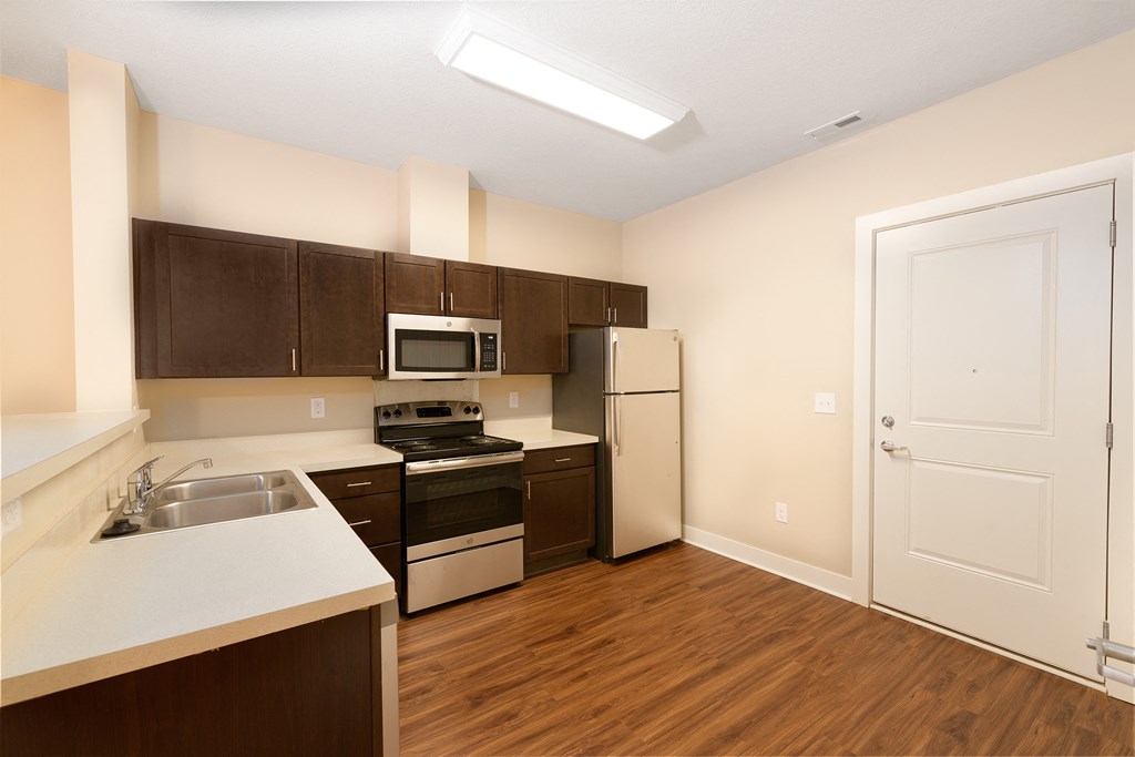 a kitchen with white appliances and wooden flooring and a white door