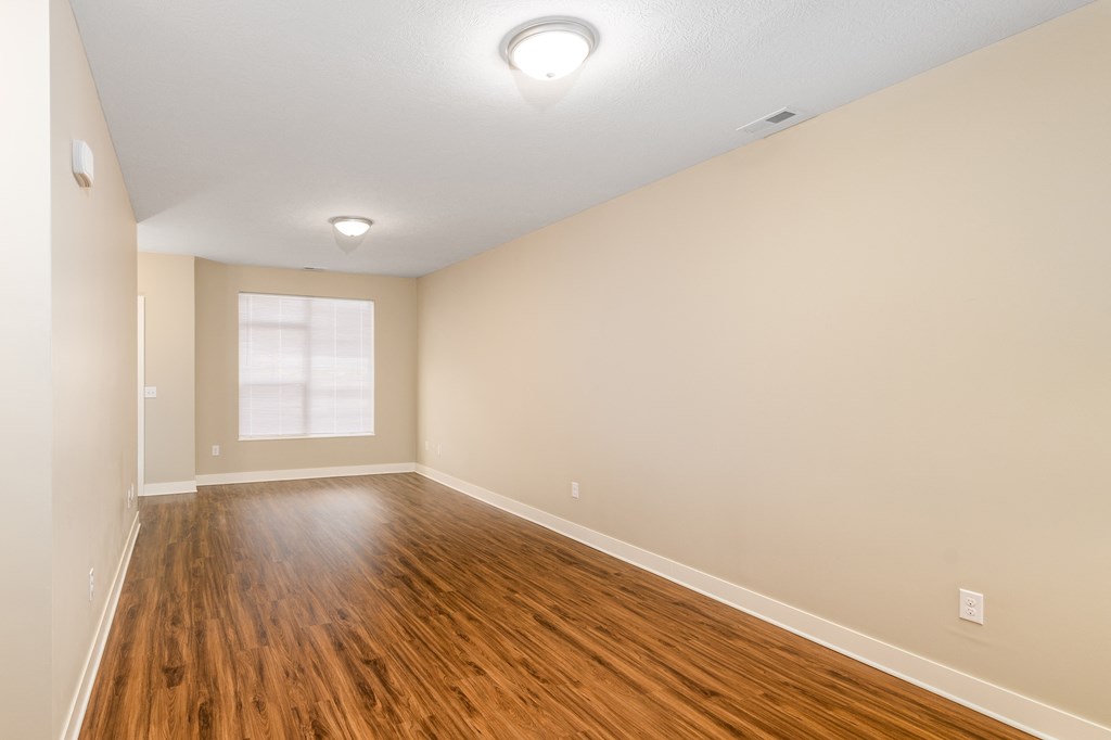 an empty living room with wood floors and a window