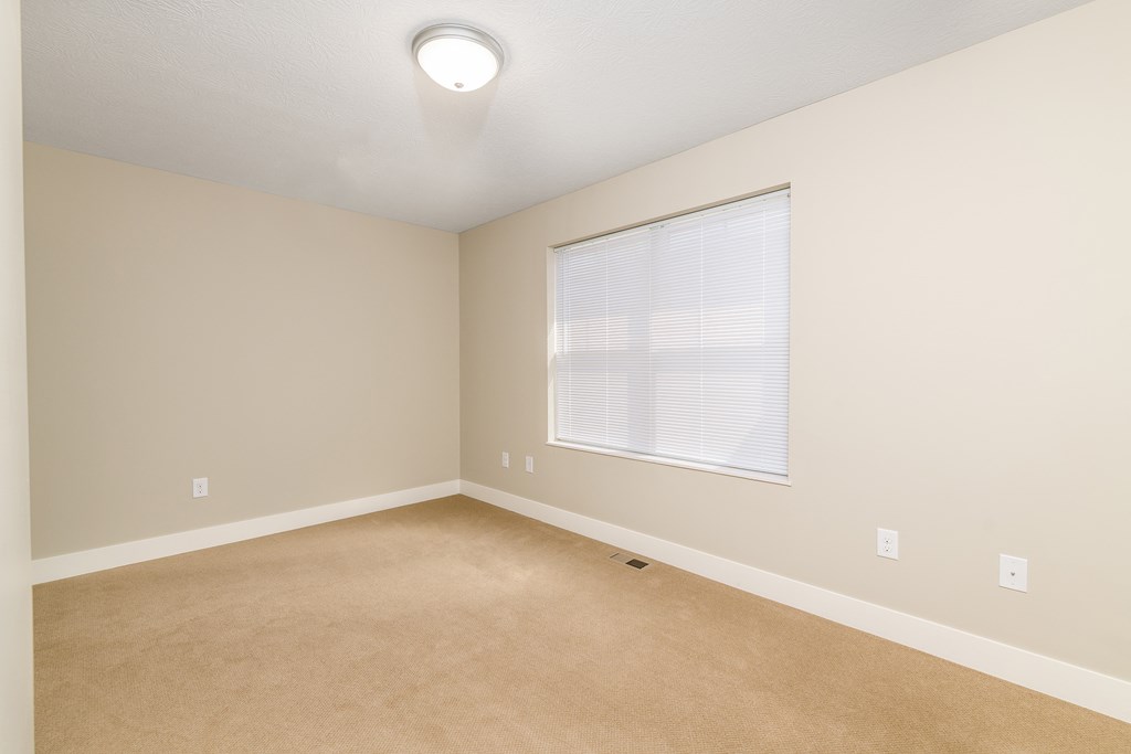 an empty living room with a large window and carpet