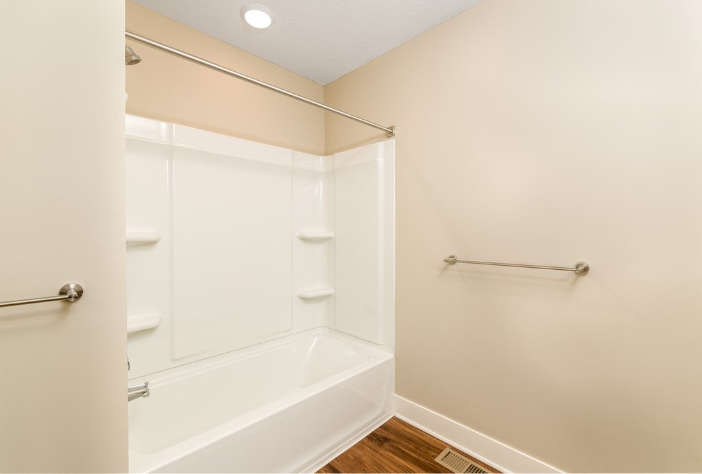 a bathroom with a tub and shower and a towel rack
