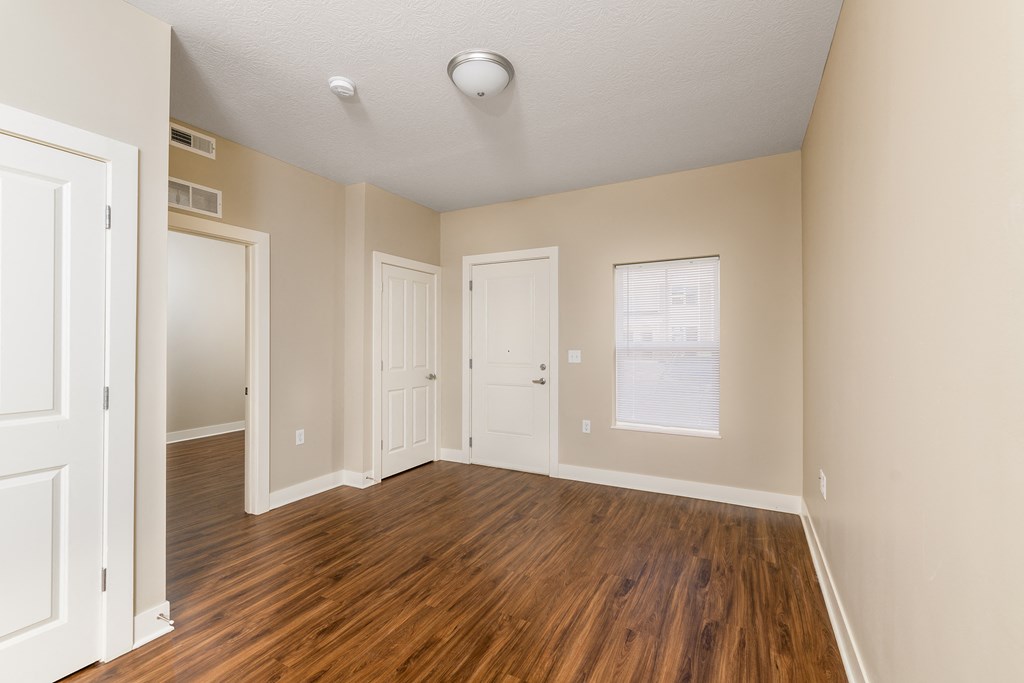 an empty living room with wood flooring and white doors