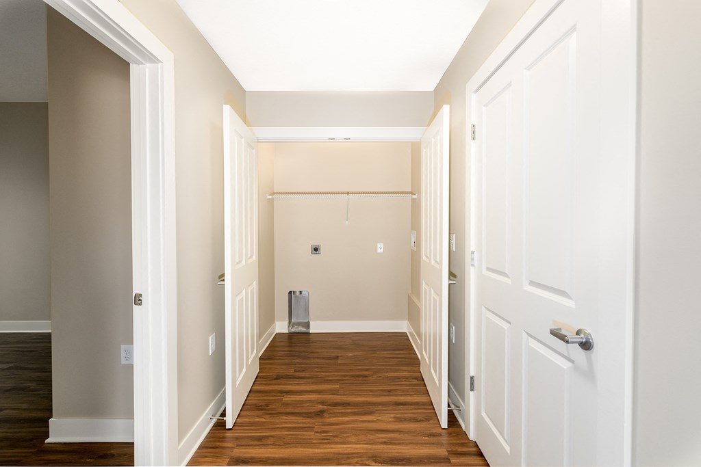 an empty hallway with wood floors and white doors