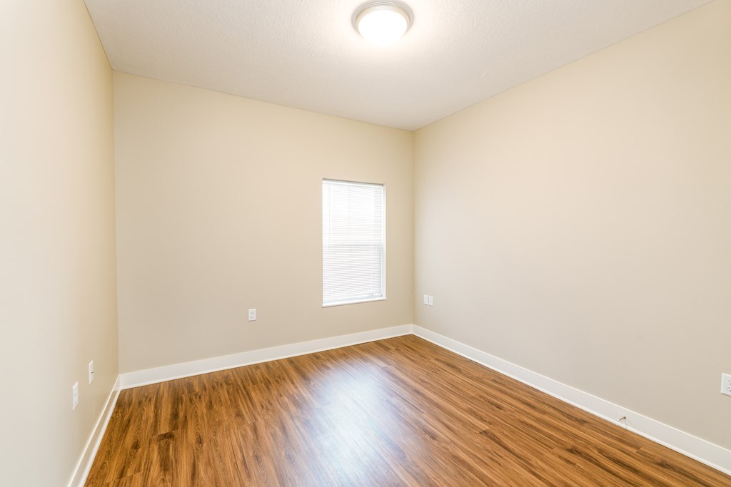 an empty living room with wood floors and a window