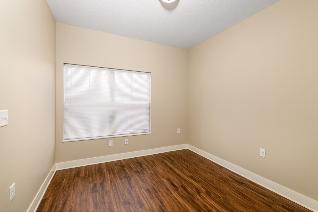 an empty room with hard wood flooring and a window