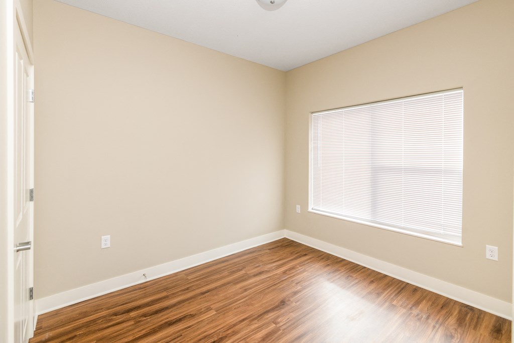 an empty room with wood floors and a large window