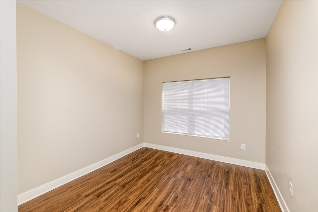 an empty room with wood floors and a window