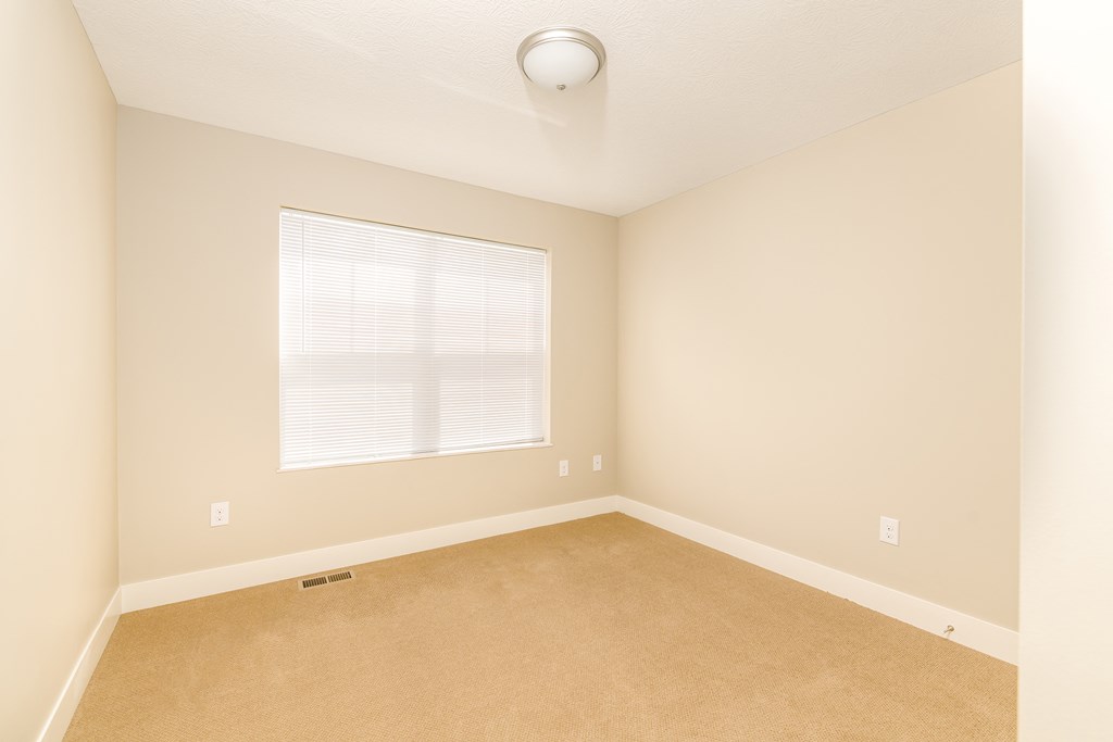 an empty room with a large window and carpet