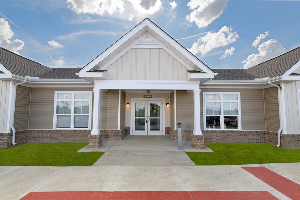 the exterior of a beige and white home with a driveway and grass