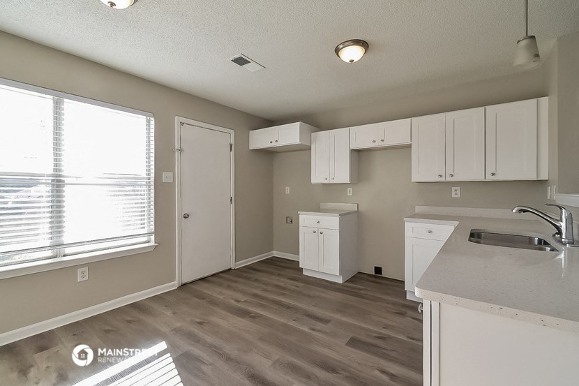 an empty kitchen with white cabinets and a window