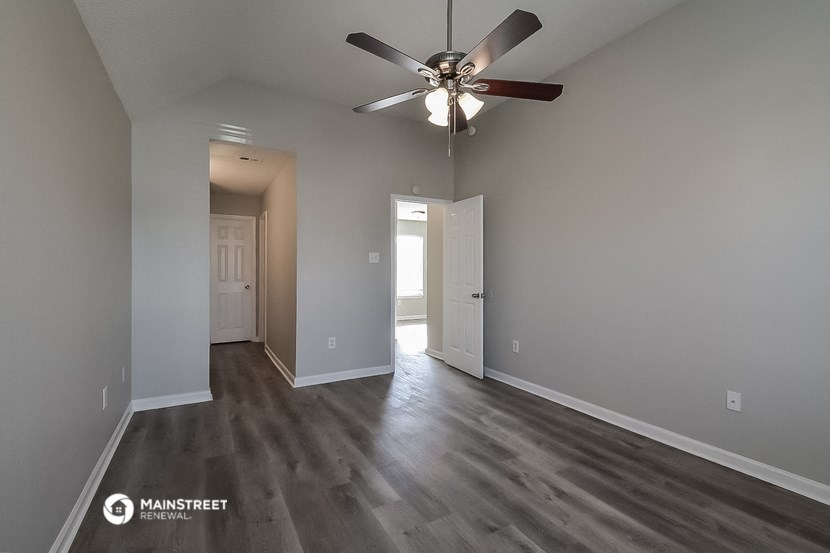 a spacious living room with gray walls and a ceiling fan