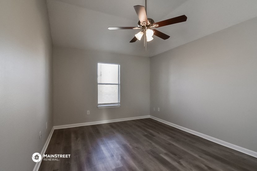 an empty room with a ceiling fan and a window