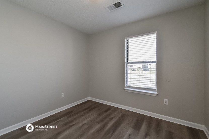 the interior of a bedroom with wooden floors and a window