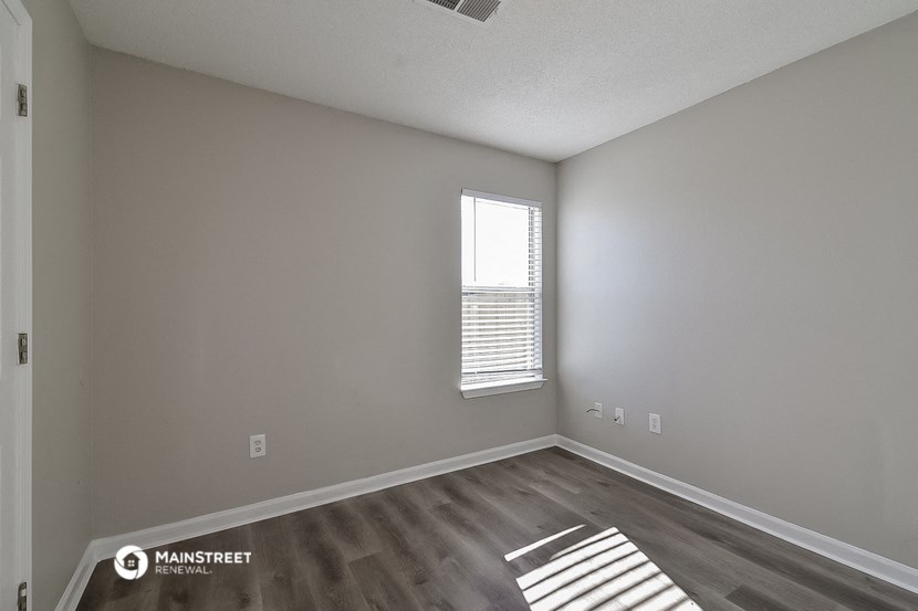 the interior of an empty room with wood flooring and a window