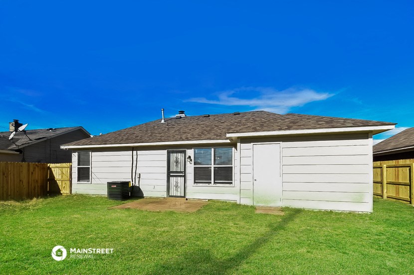 the backyard of a white house with a yard and a fence