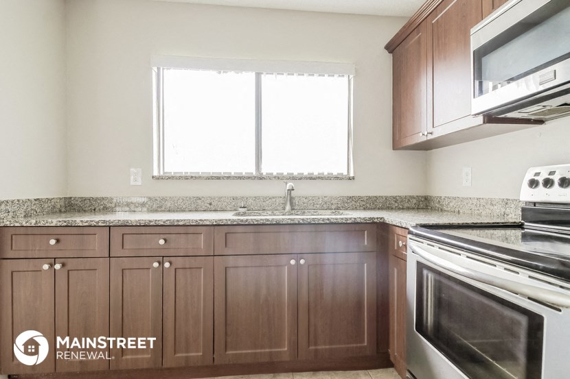 an empty kitchen with wooden cabinets and a window