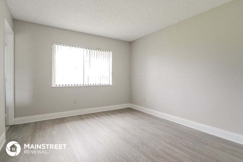 the spacious living room with wood flooring and a window
