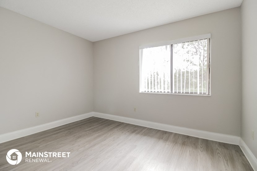 the upstairs bedroom with wood flooring and a large window