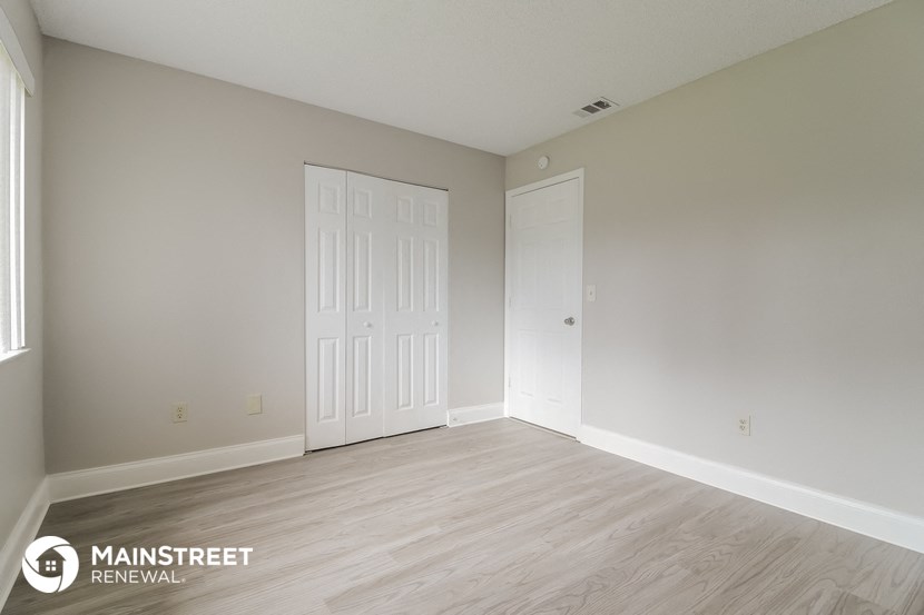 the spacious living room with white doors and wood flooring
