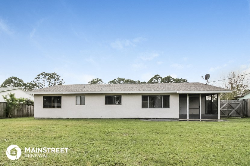 a small white house with a grassy yard and a satellite dish on the roof