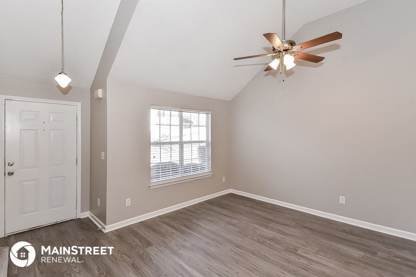 the spacious living room with ceiling fan and wood flooring