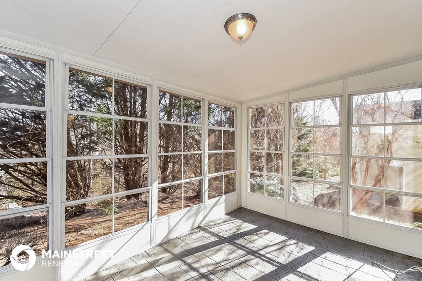 a sun room with large windows and a view of the woods