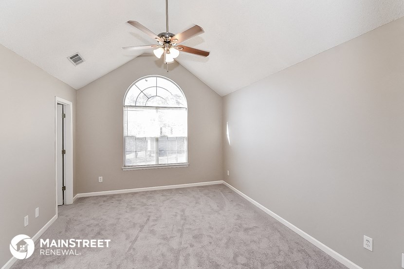 the master bedroom has a large window and carpeted flooring