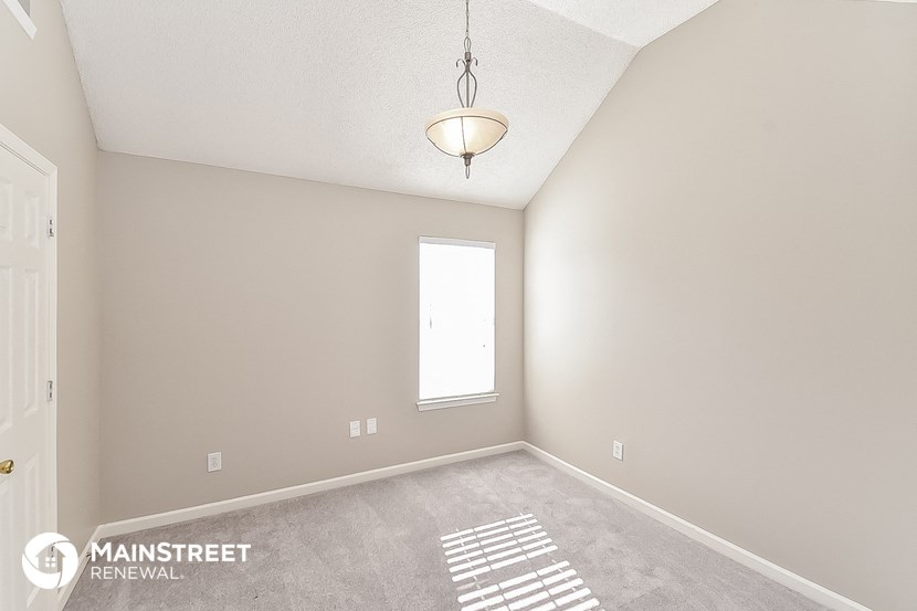 the spacious living room with carpeted flooring and a window