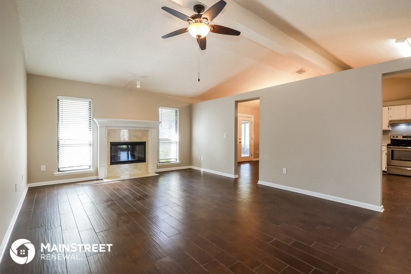an empty living room with a fireplace and a ceiling fan