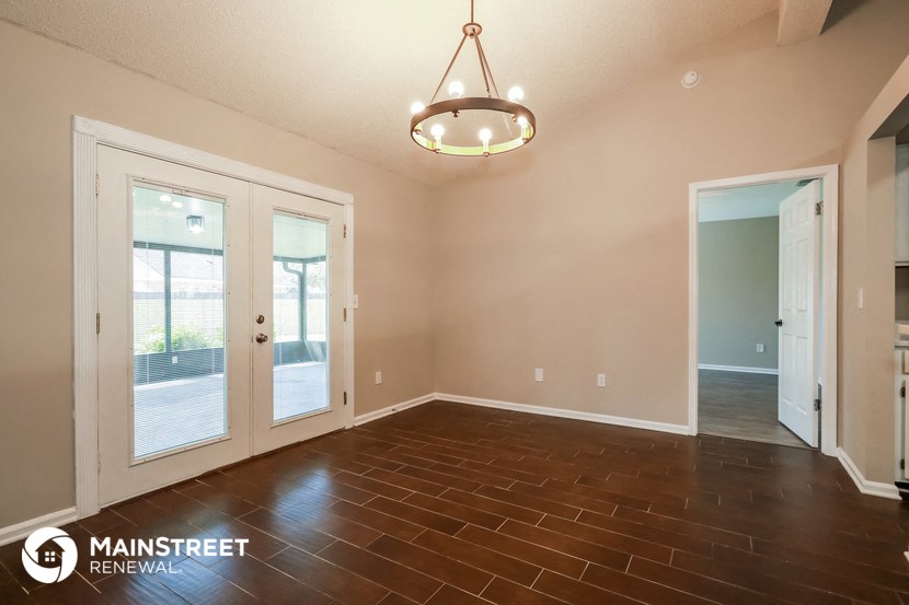 an empty living room with wood floors and a chandelier