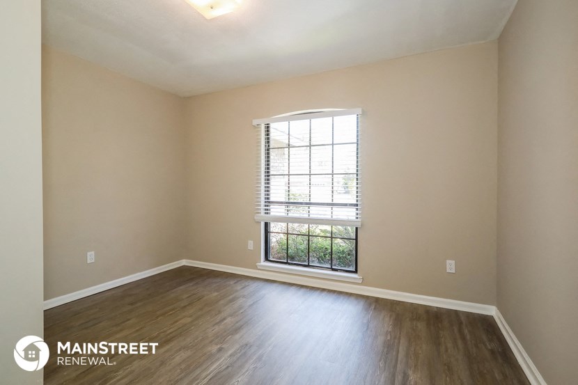 the spacious living room with wood flooring and a large window