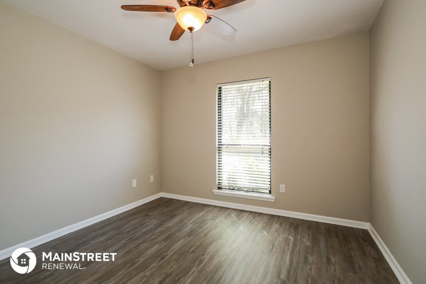 the spacious living room with wood flooring and a ceiling fan