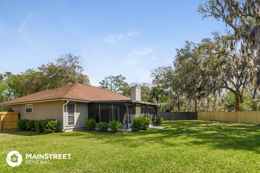 a small house with a yard and a fence and trees