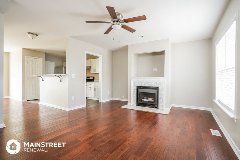 an empty living room with a fireplace and a ceiling fan