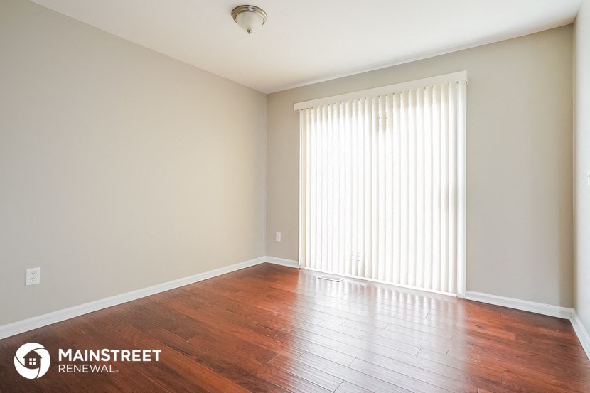 the spacious living room with wood flooring and a large window