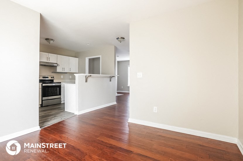 a living room and kitchen with wood flooring and white walls