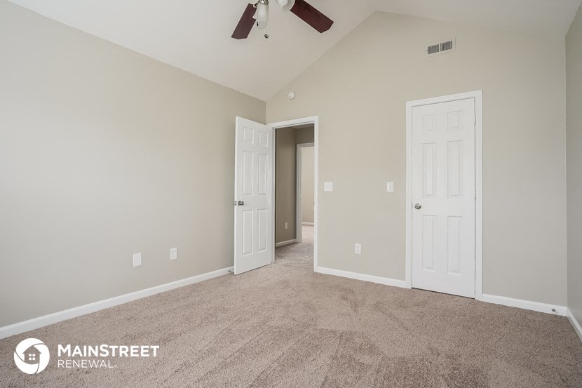 the spacious living room with carpeting and a ceiling fan