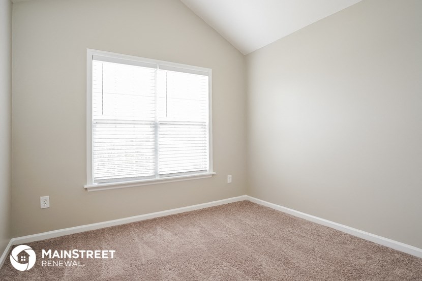 a bedroom with a window and a carpeted floor