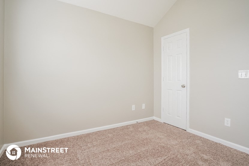 a bedroom with a door and a carpeted floor