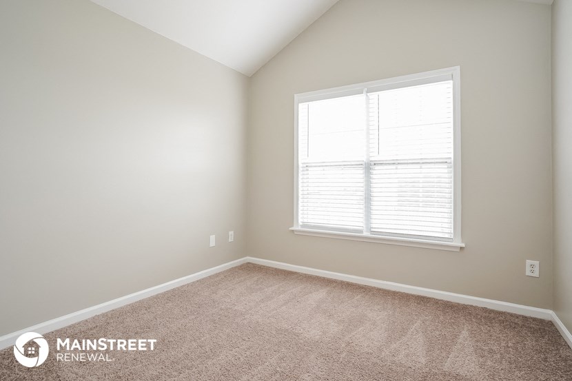 a bedroom with a large window and a carpeted floor