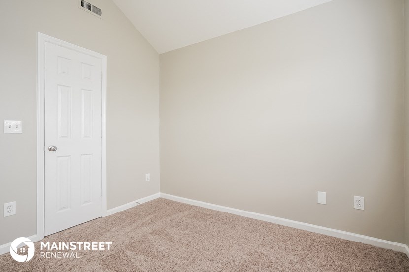 a bedroom with a white door and a carpeted floor