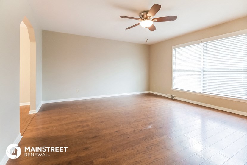 an empty living room with wood floors and a ceiling fan