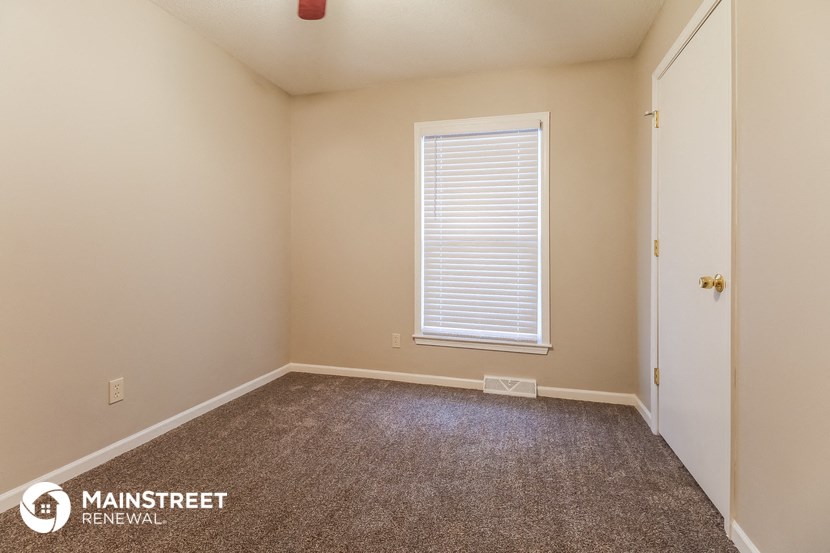 the upstairs bedroom with carpeted flooring and a window