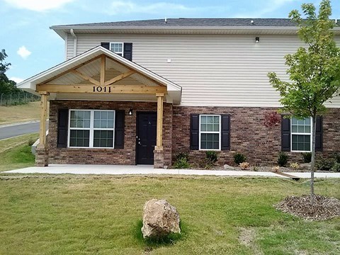 a house with a porch and a rock in front of it