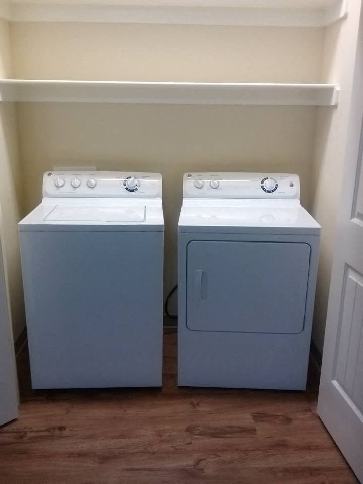 two washers and dryers in a room with a wooden floor