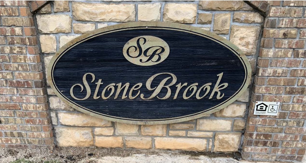 a sign for stone brook on a brick wall