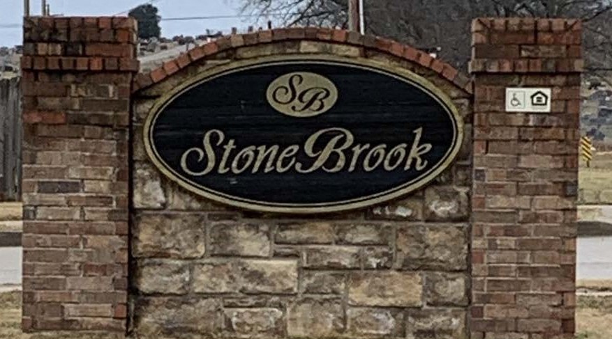 a stone brick wall with a stone brook sign on it